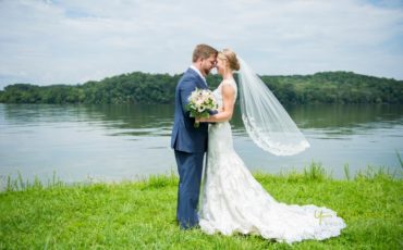 Bride and groom embrace by water at Whitestone Inn