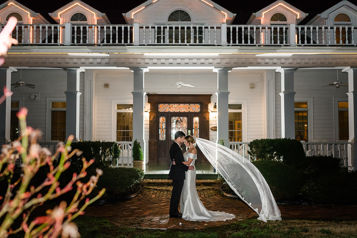 Bridge and groom pose in front of Farmhouse at night