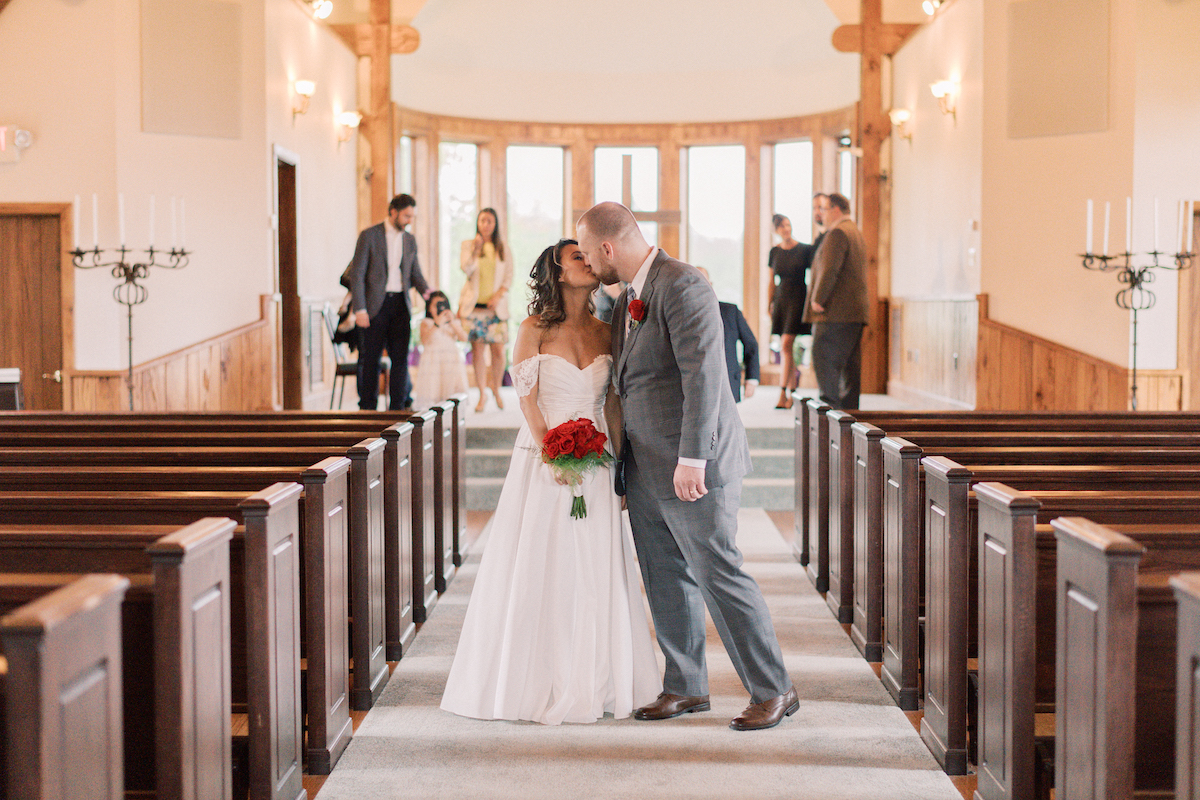 Bride and groom kiss in the aisle of the Chapel