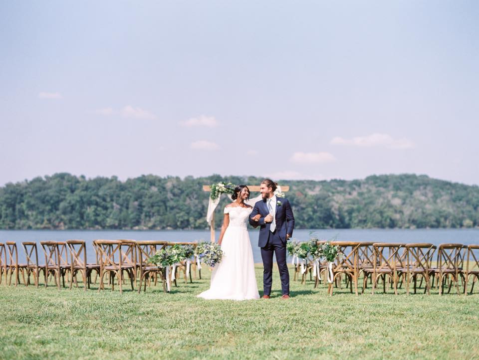 Bride and groom pose in front of wedding setup on shore of Watts Bar lake