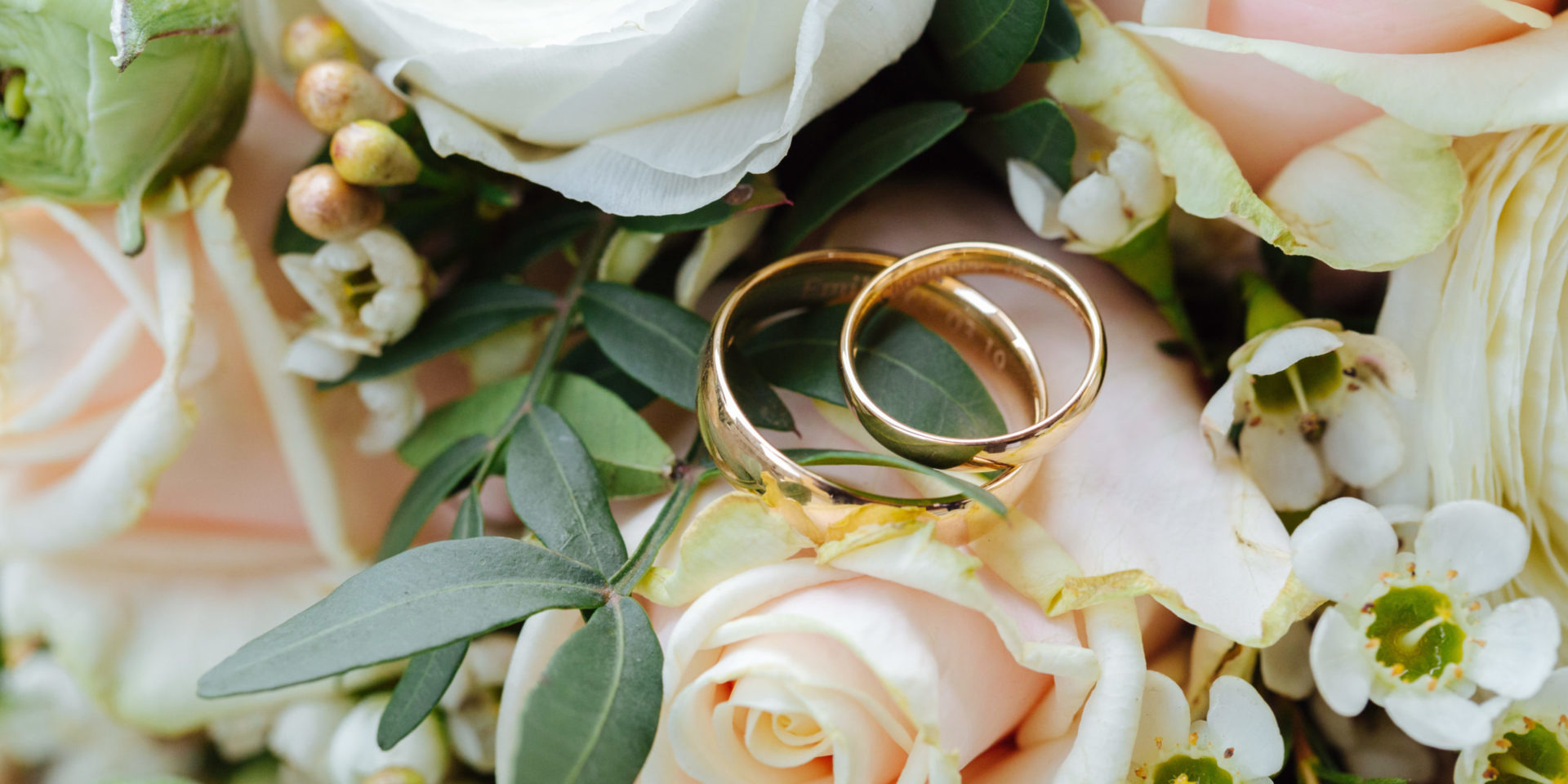 Close up of two gold wedding bands placed on a bridal bouquet