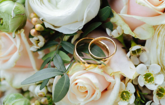 Close up of two gold wedding bands placed on a bridal bouquet