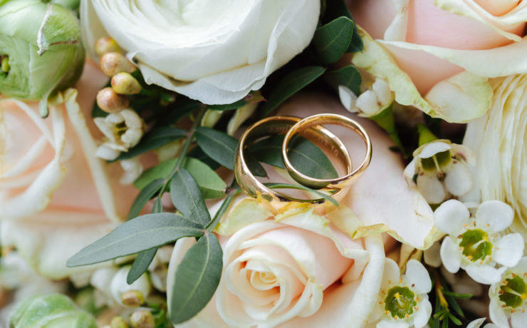 Close up of two gold wedding bands placed on a bridal bouquet