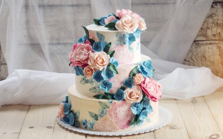 Wedding cake feature colorful flower decorations against a white lace background
