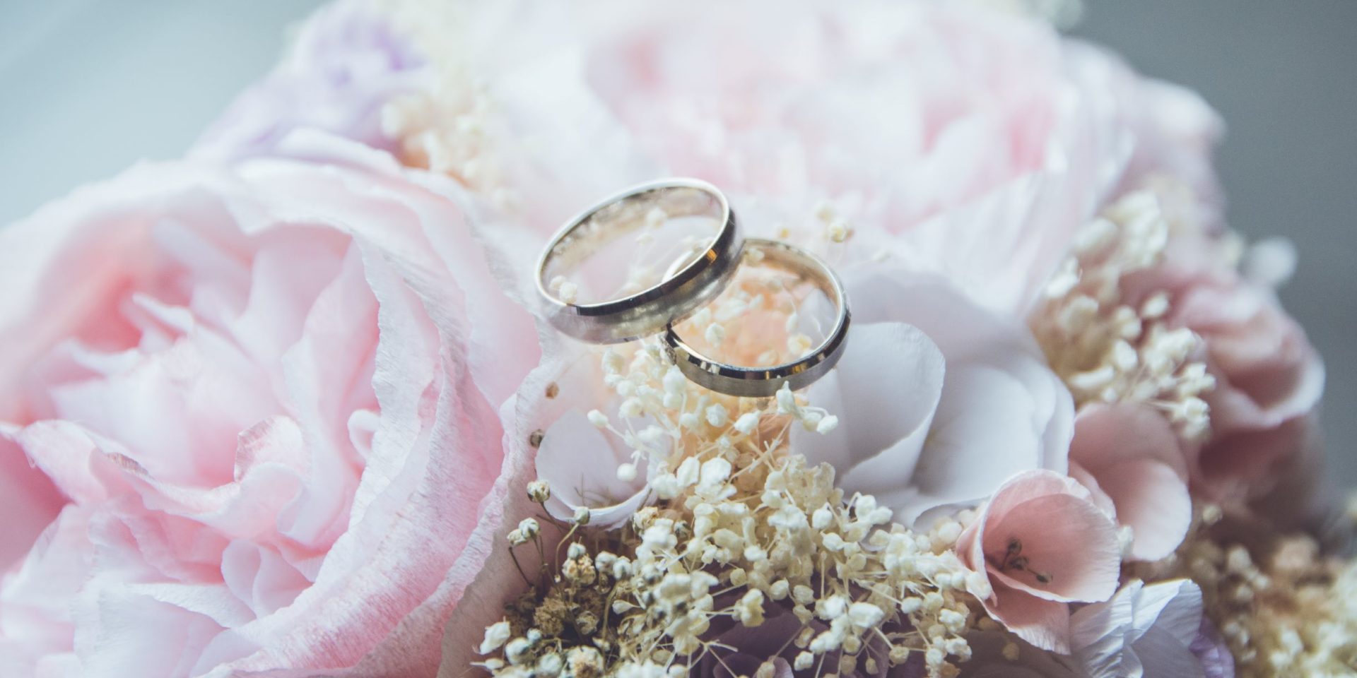 A close up of two weddings rings resting on top of a bridal bouquet