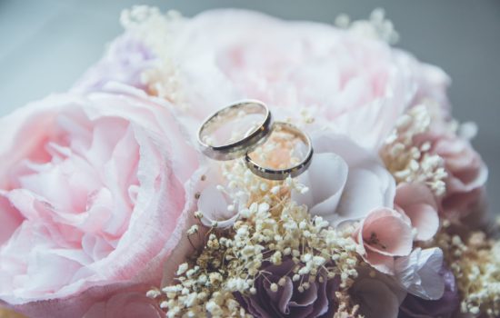 A close up of two weddings rings resting on top of a bridal bouquet
